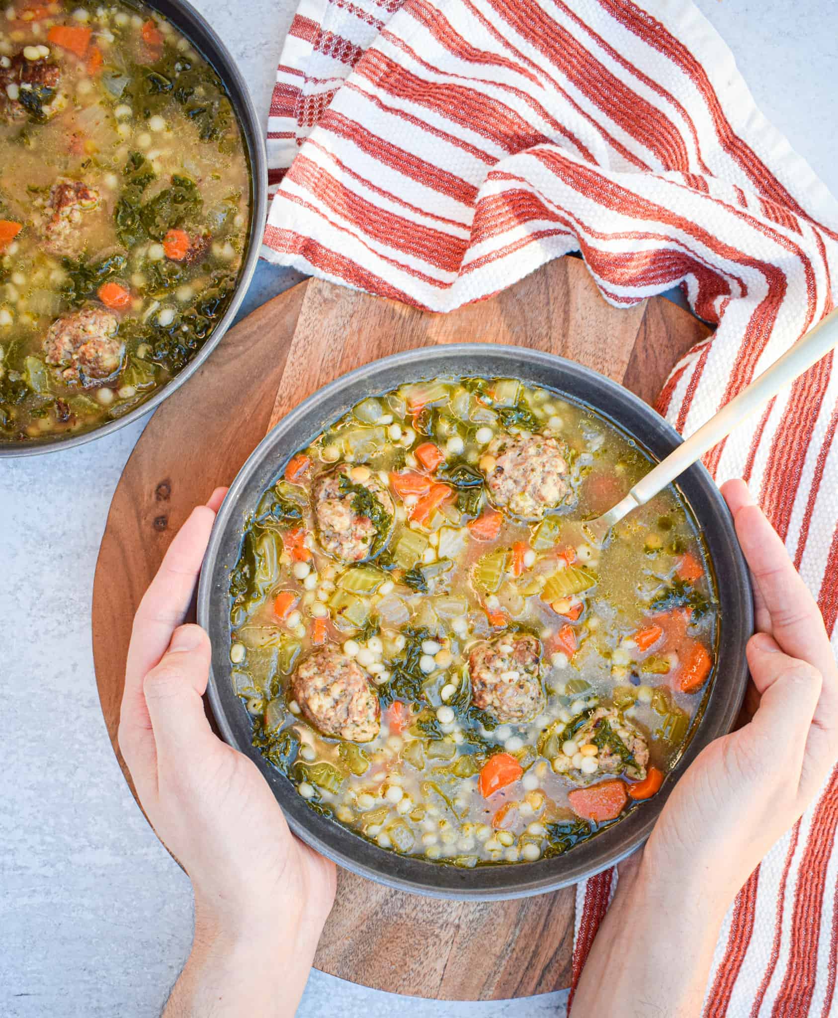 bowl of italian wedding soup with couscous and meatballs and kale