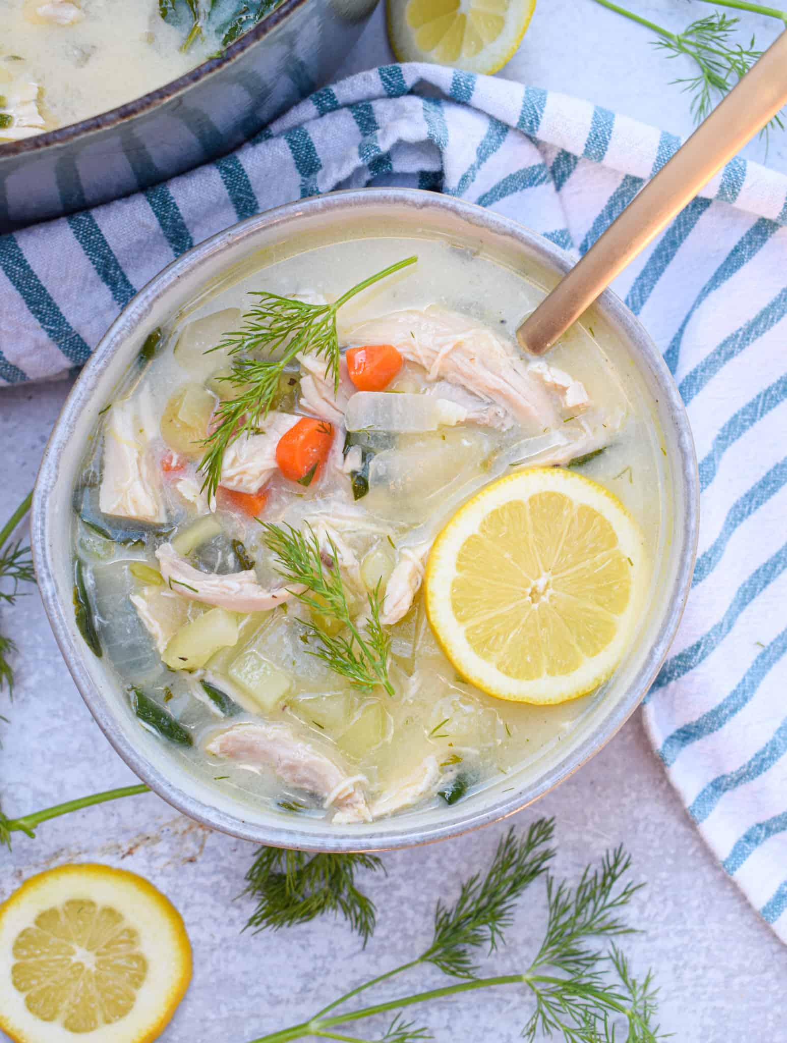 Bowl of Whole30 Greek Lemon Chicken Soup with slices of lemon and fresh dill sprigs 