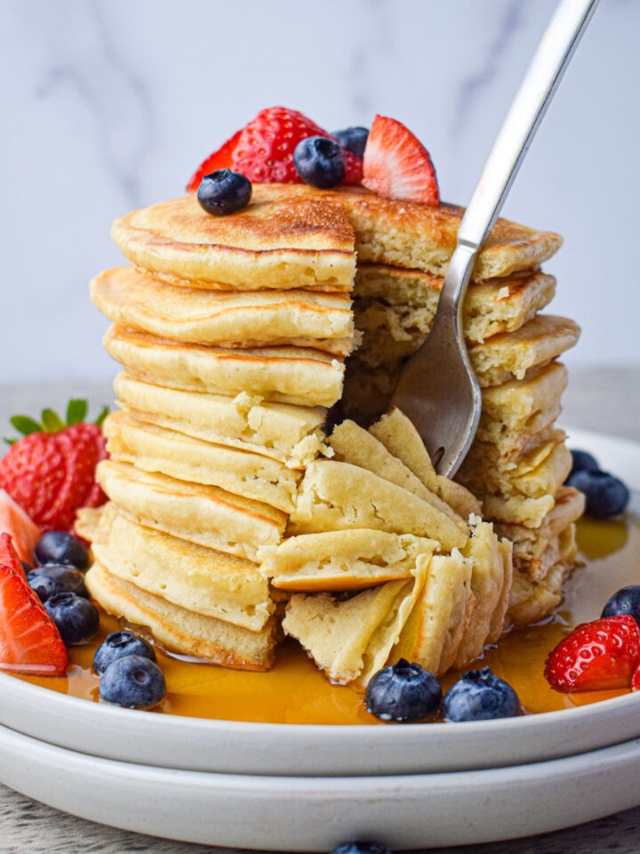 stack of dairy free pancakes with berries and syrup