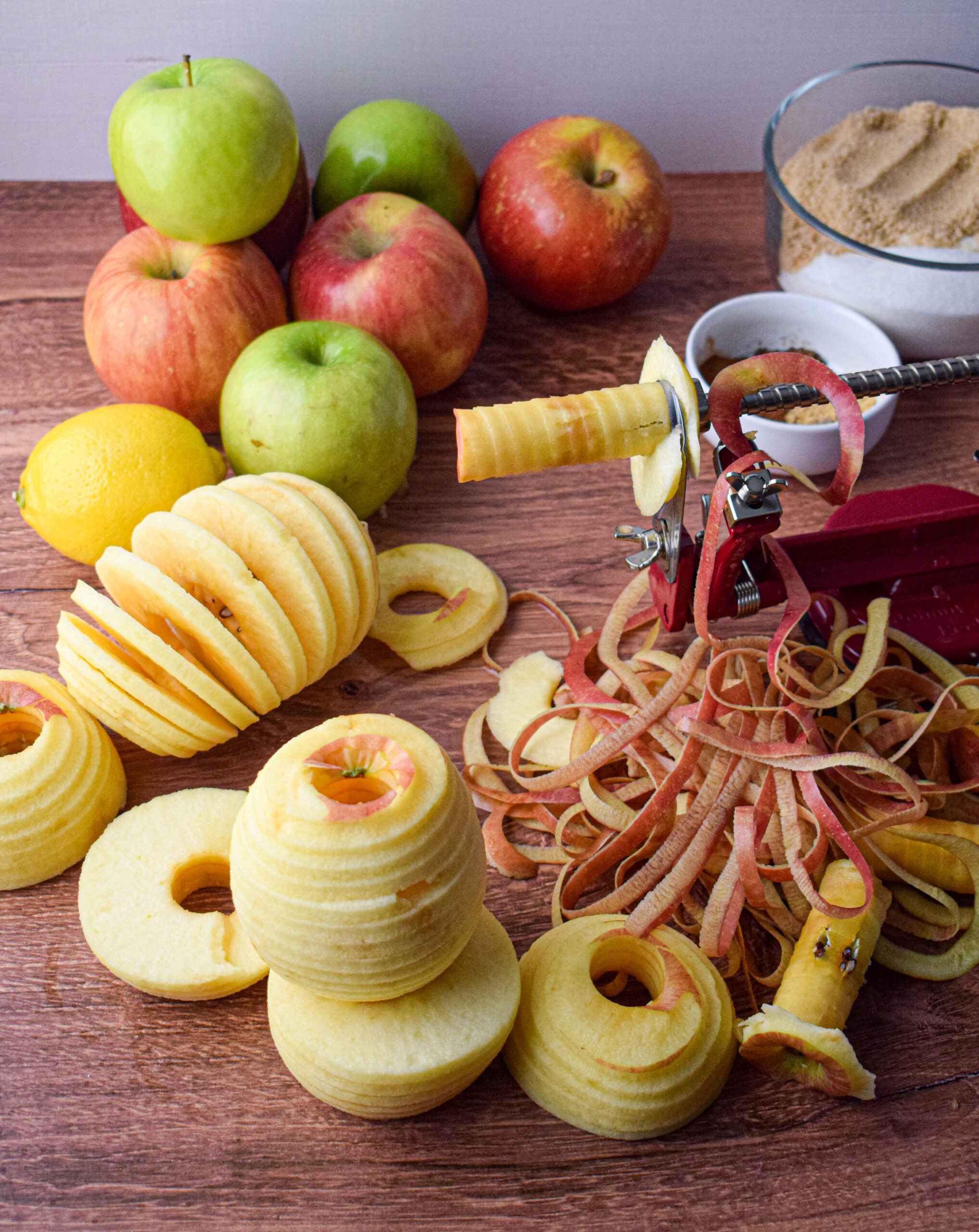 apple peeler with peeled sliced apples all around it for apple butter