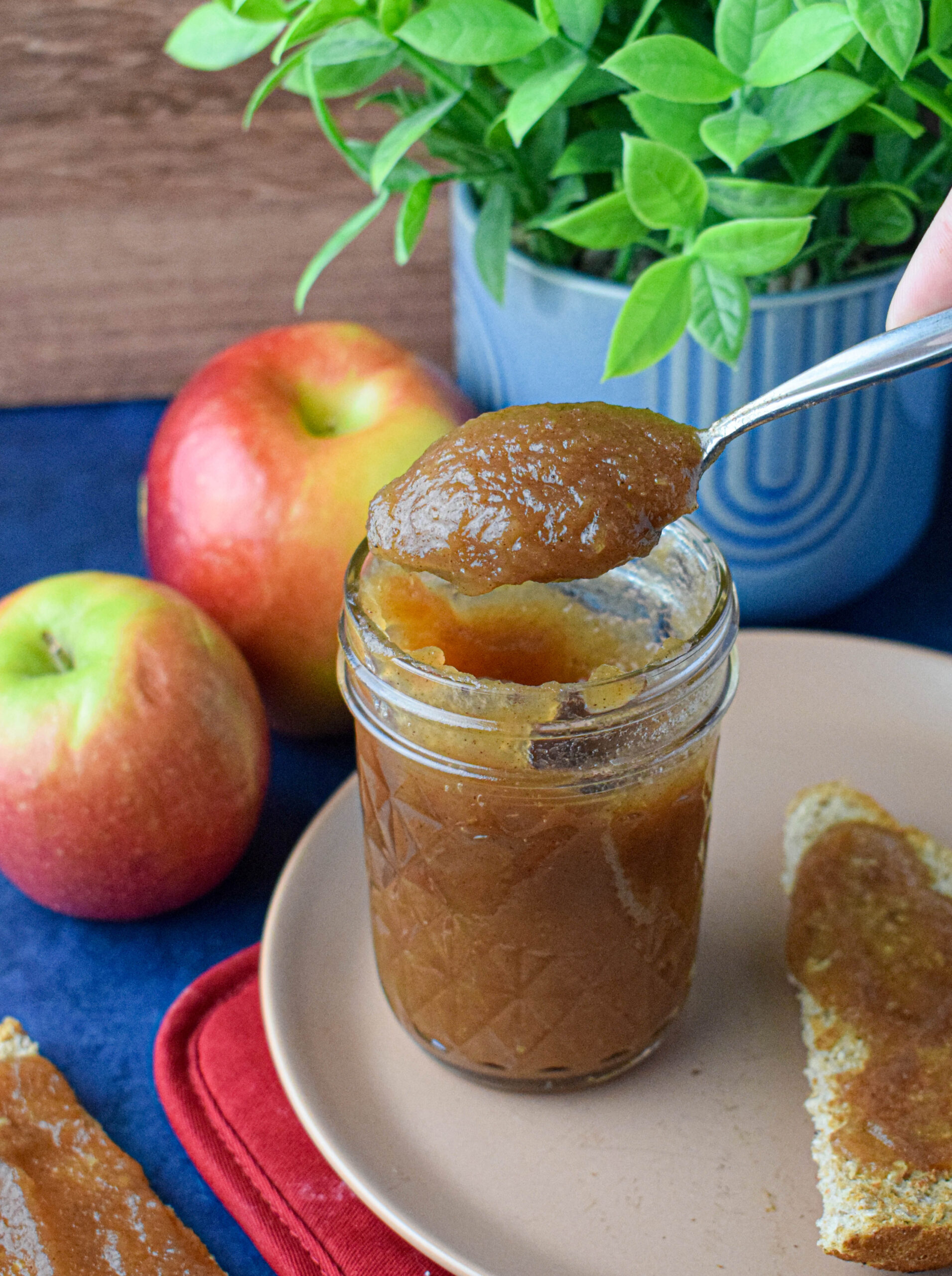 mason jar full of apple butter next to apples and toast with apple butter spread on it 