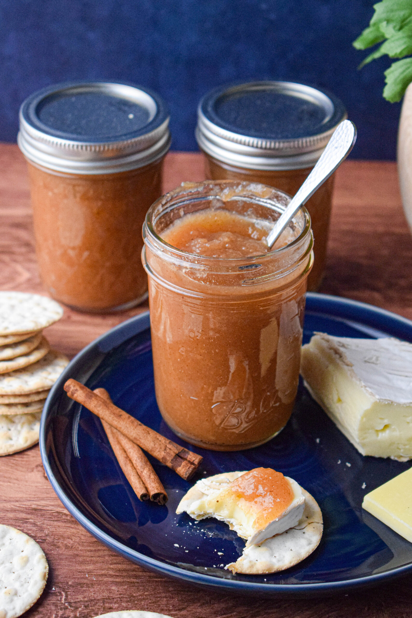 mason jars of spiced pear butter on a blue plate with crackers and cheese