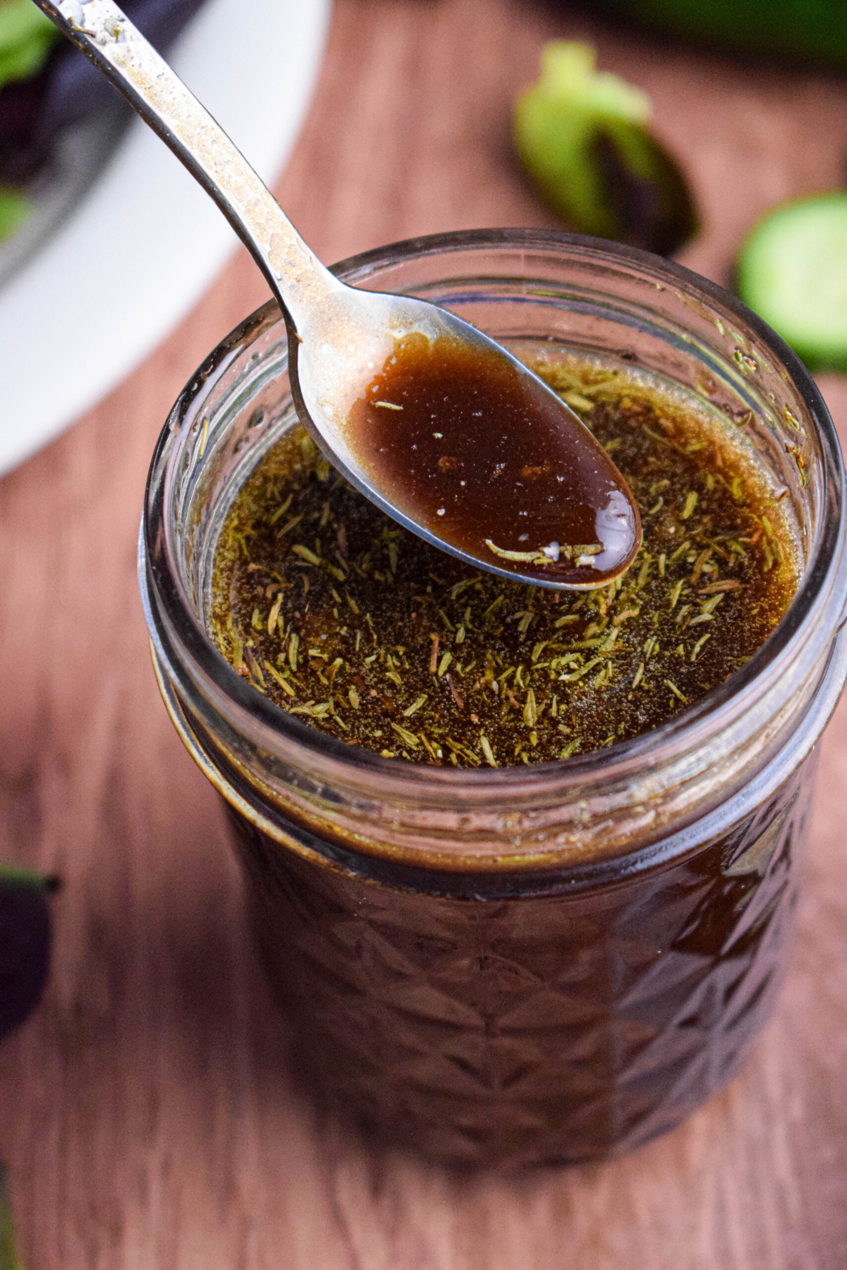 mason jar with balsamic maple dressing with a spoon pouring the dressing 
