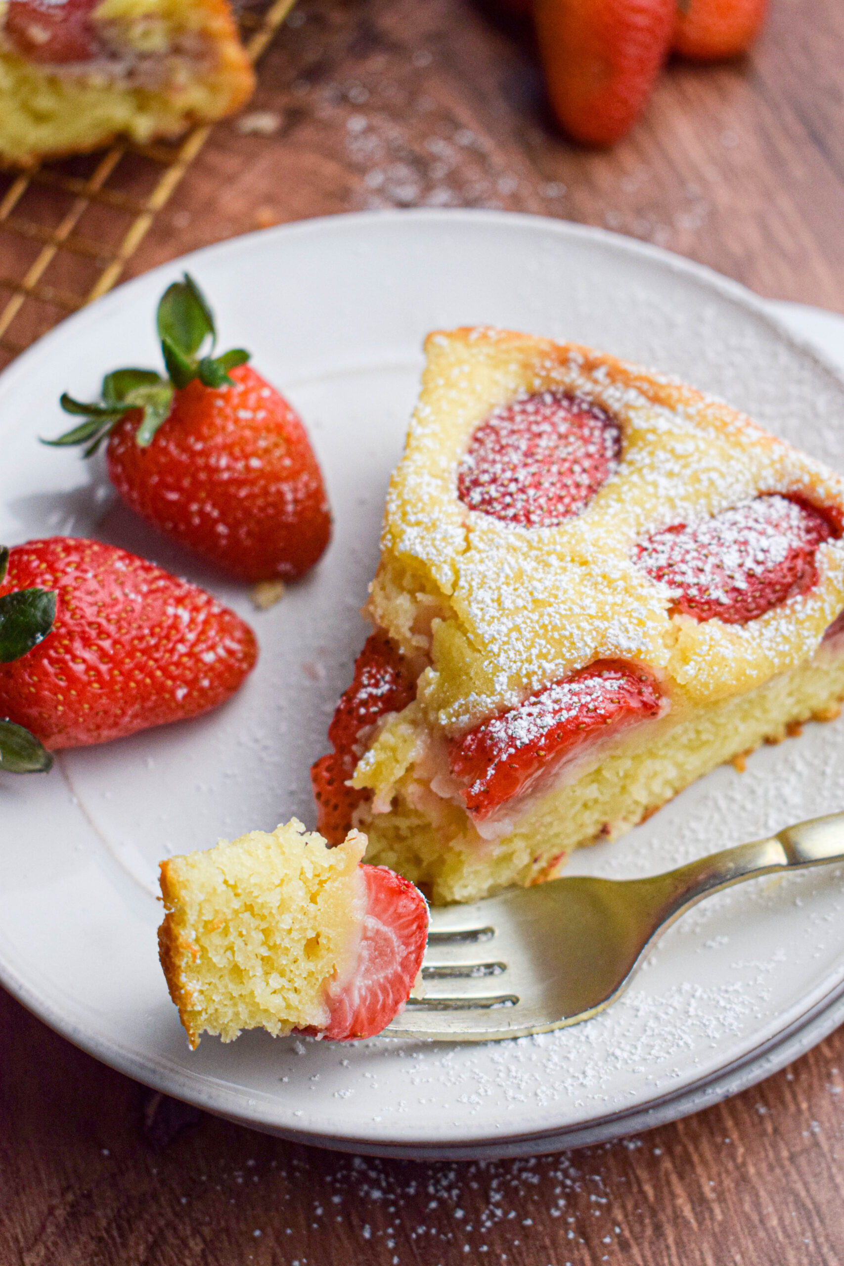 slice of strawberry and yogurt cake on a cake plate with fresh strawberries 