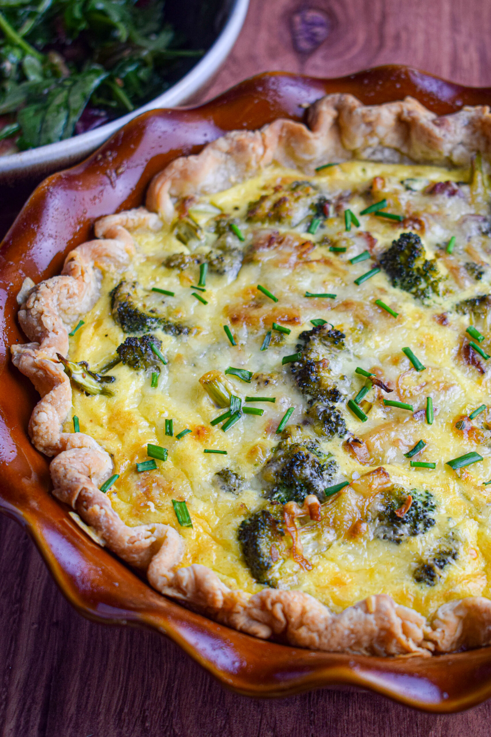 baked broccoli cheddar quiche topped with cheese and chives 
