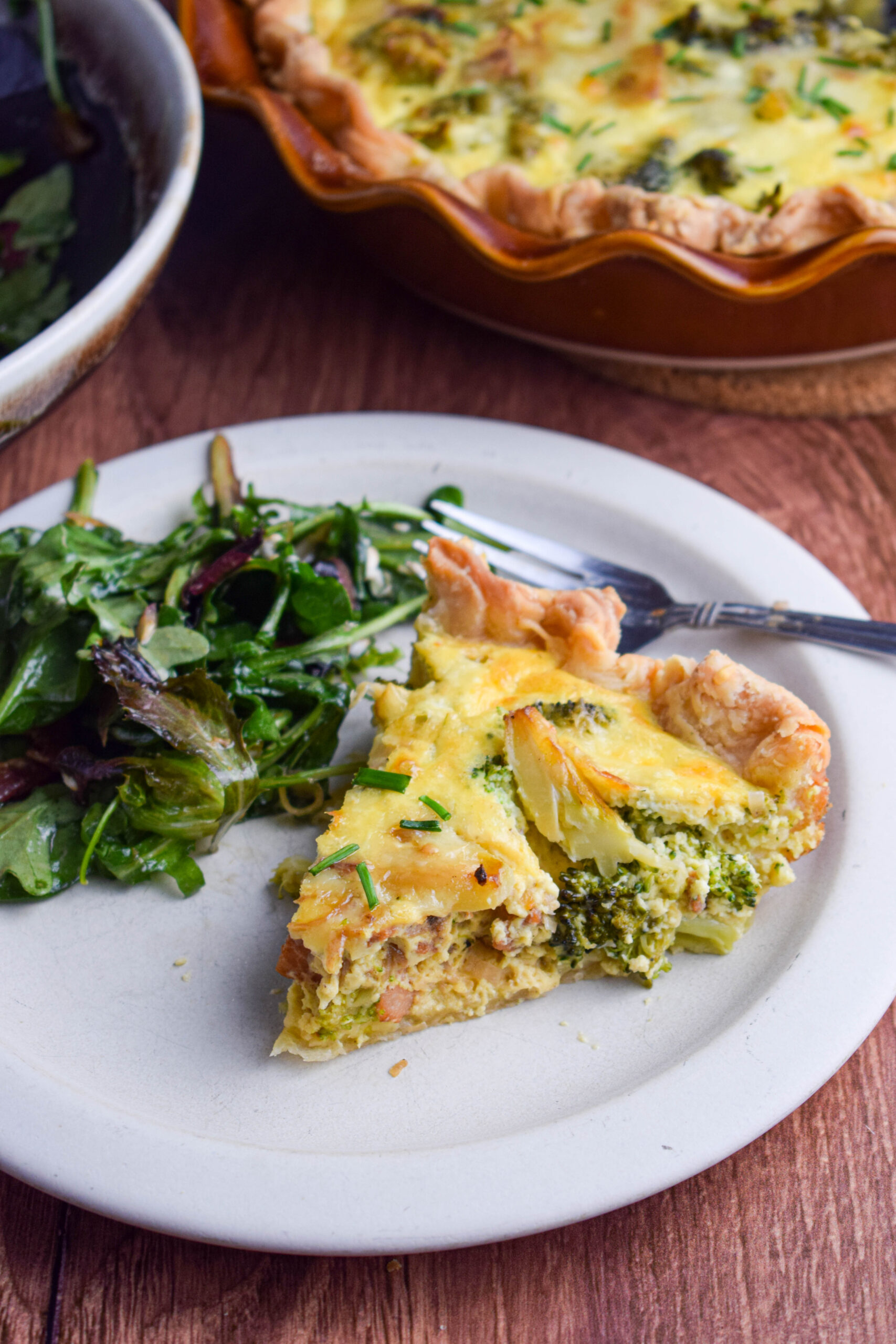plate with salad and broccoli cheese and bacon quiche