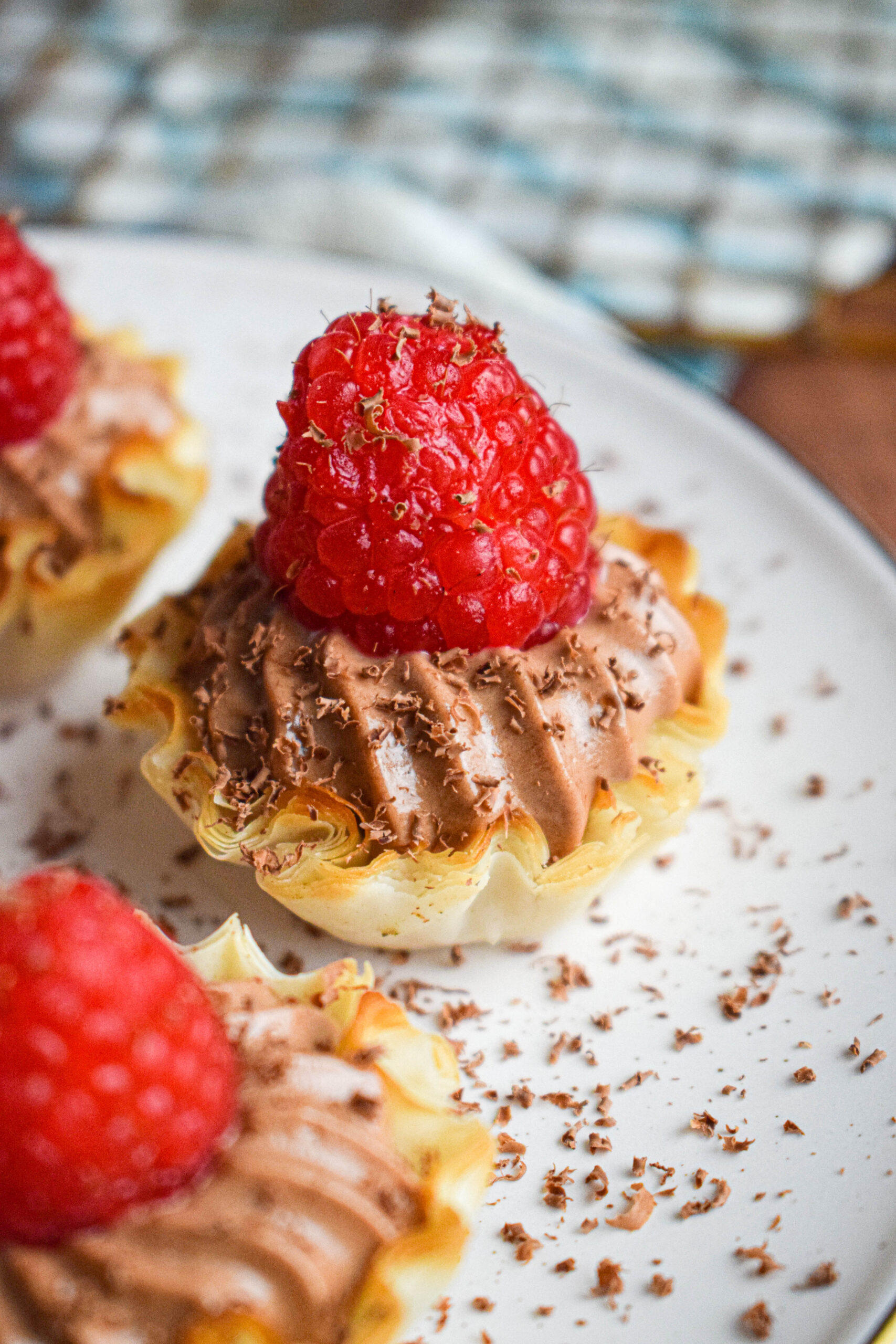 close up shot of a mini nutella tartlet topped with raspberry and dark chocolate 