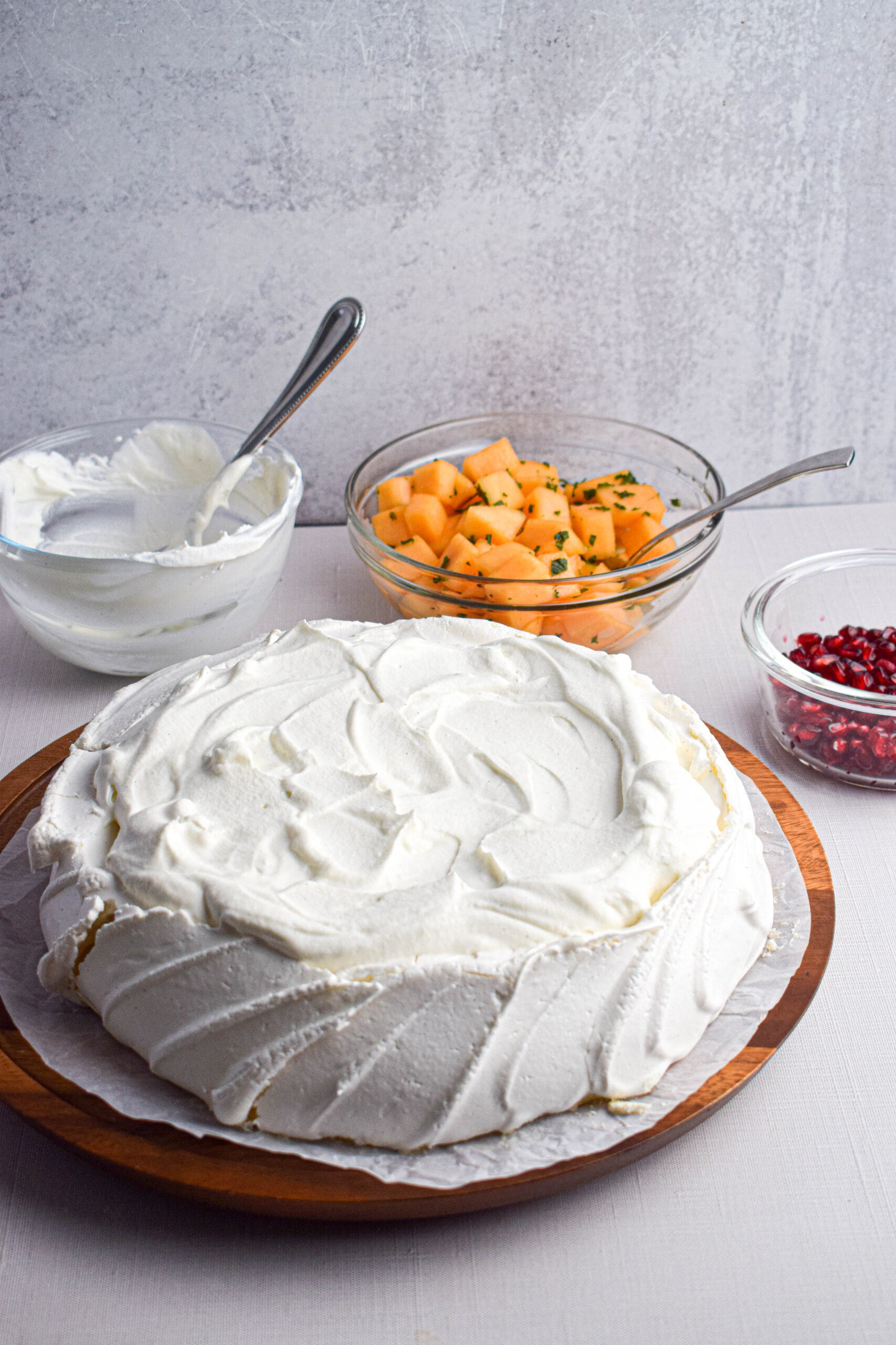 meringue filled with whipped cream next to a bowl of cantaloupe melon