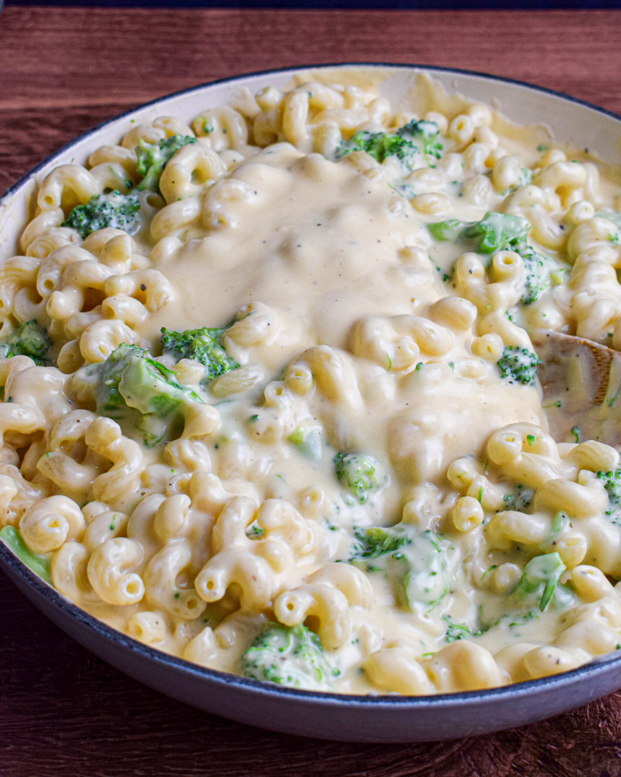 Large pan of pasta and broccoli that has just had a stovetop cheese sauce poured over the top.