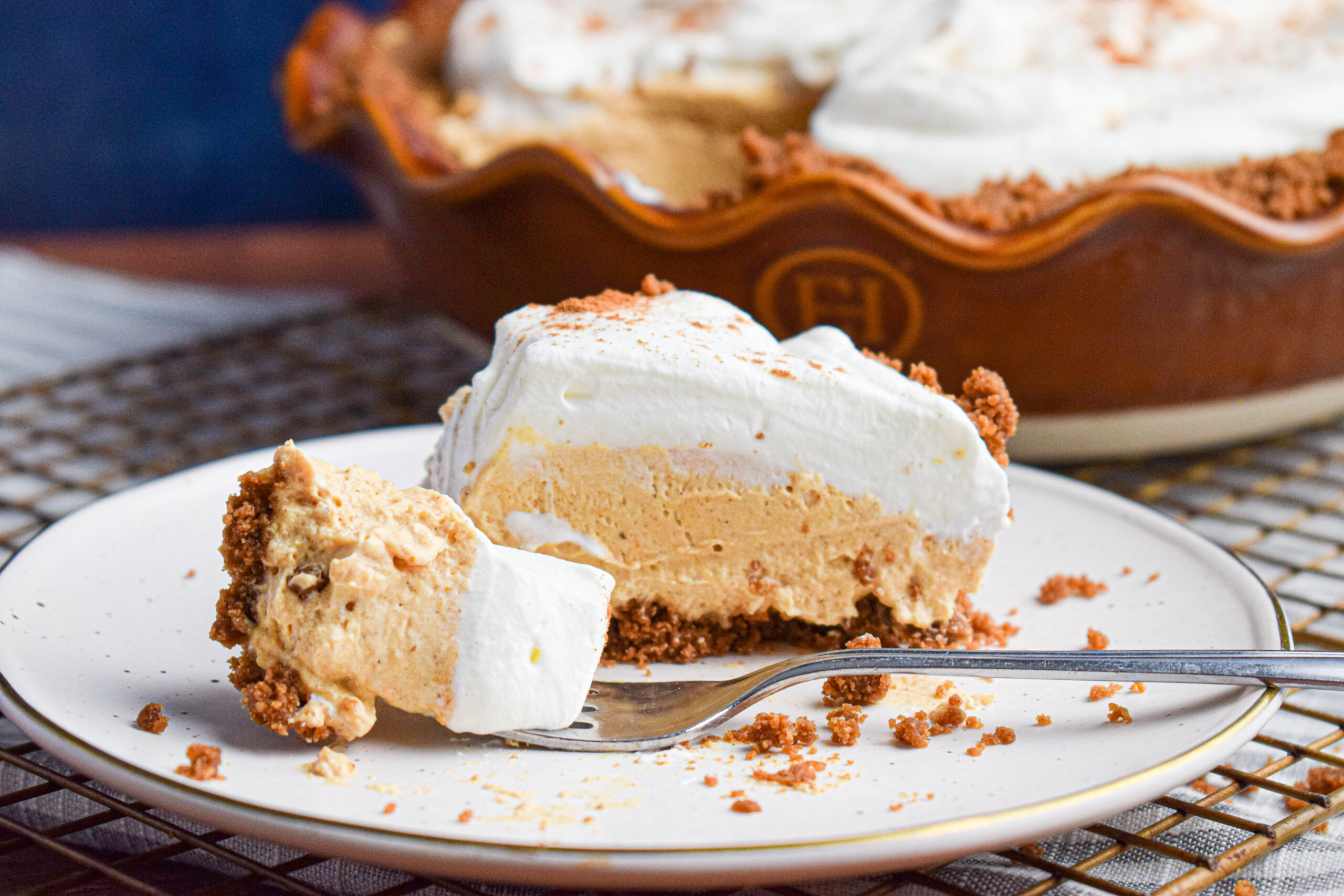 A slice of creamy no bake fall pie topped with whipped cream with a fork taking out a bite. 
