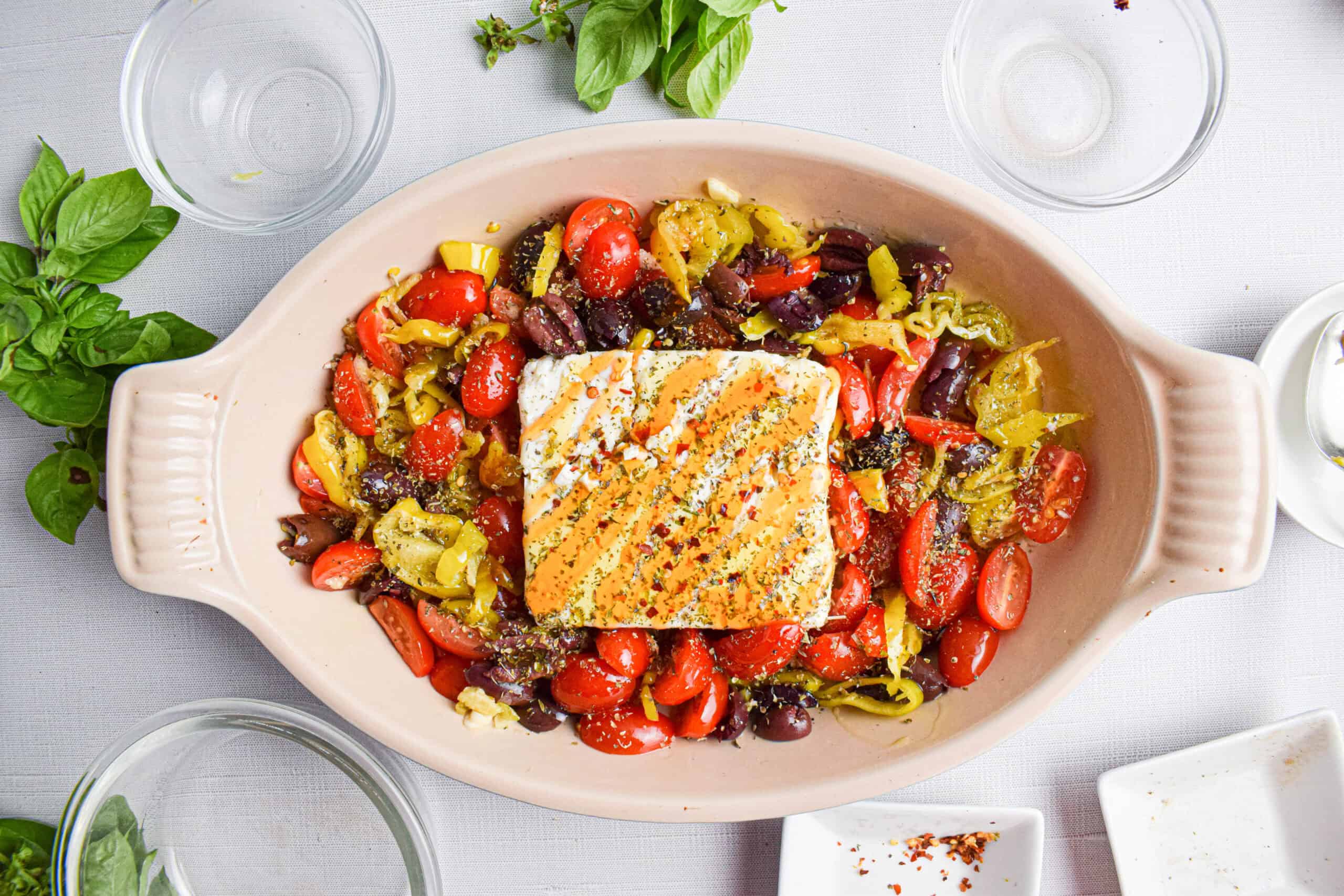 Uncooked feta with vegetables and hot honey in a baking dish. 