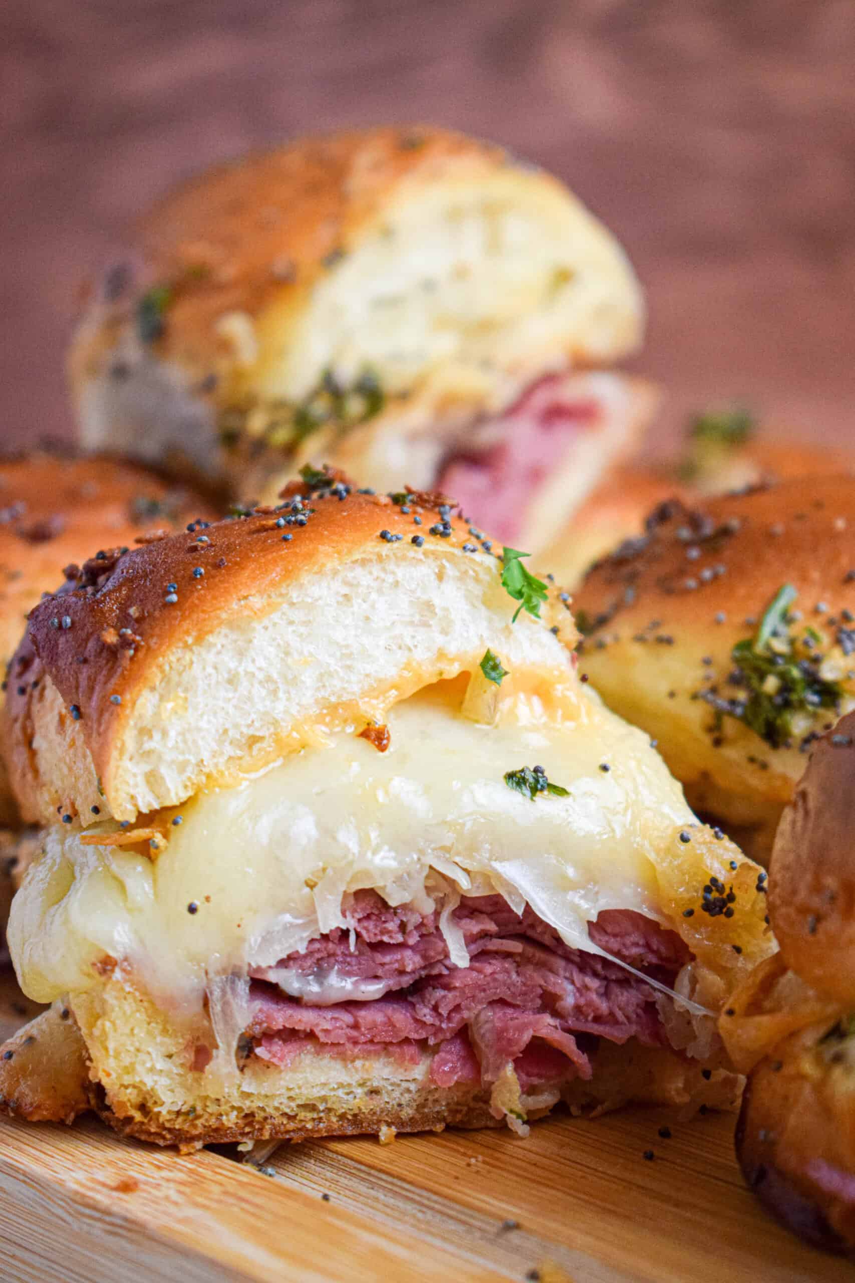 Side view of a reuben slider with a golden brown top with layers of corned beef, sauerkraut and melted cheese. 