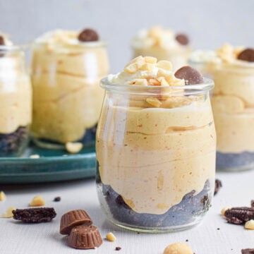 Easy and quick peanut butter mousse in small glass jars topped with cream, peanuts and chocolate.