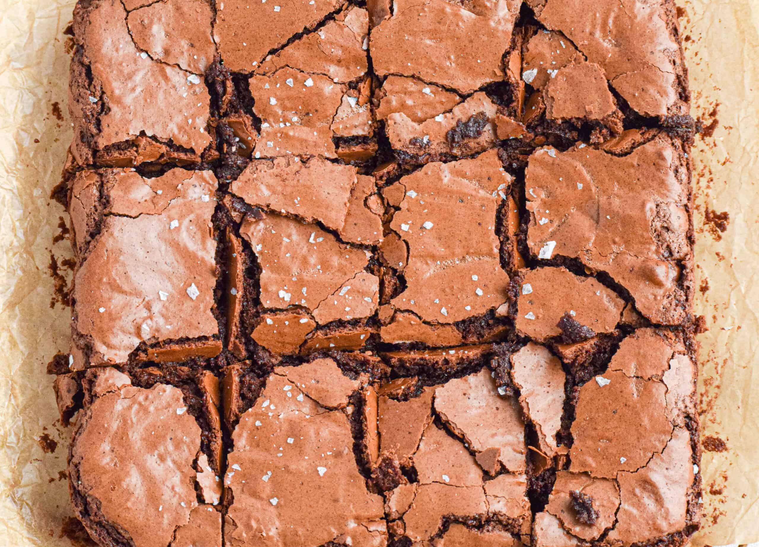 Overhead shot of baked homemade sourdough discard chocolate brownies with a crinkle crackly top and a gooey fudgy center that has been cut into squares. 