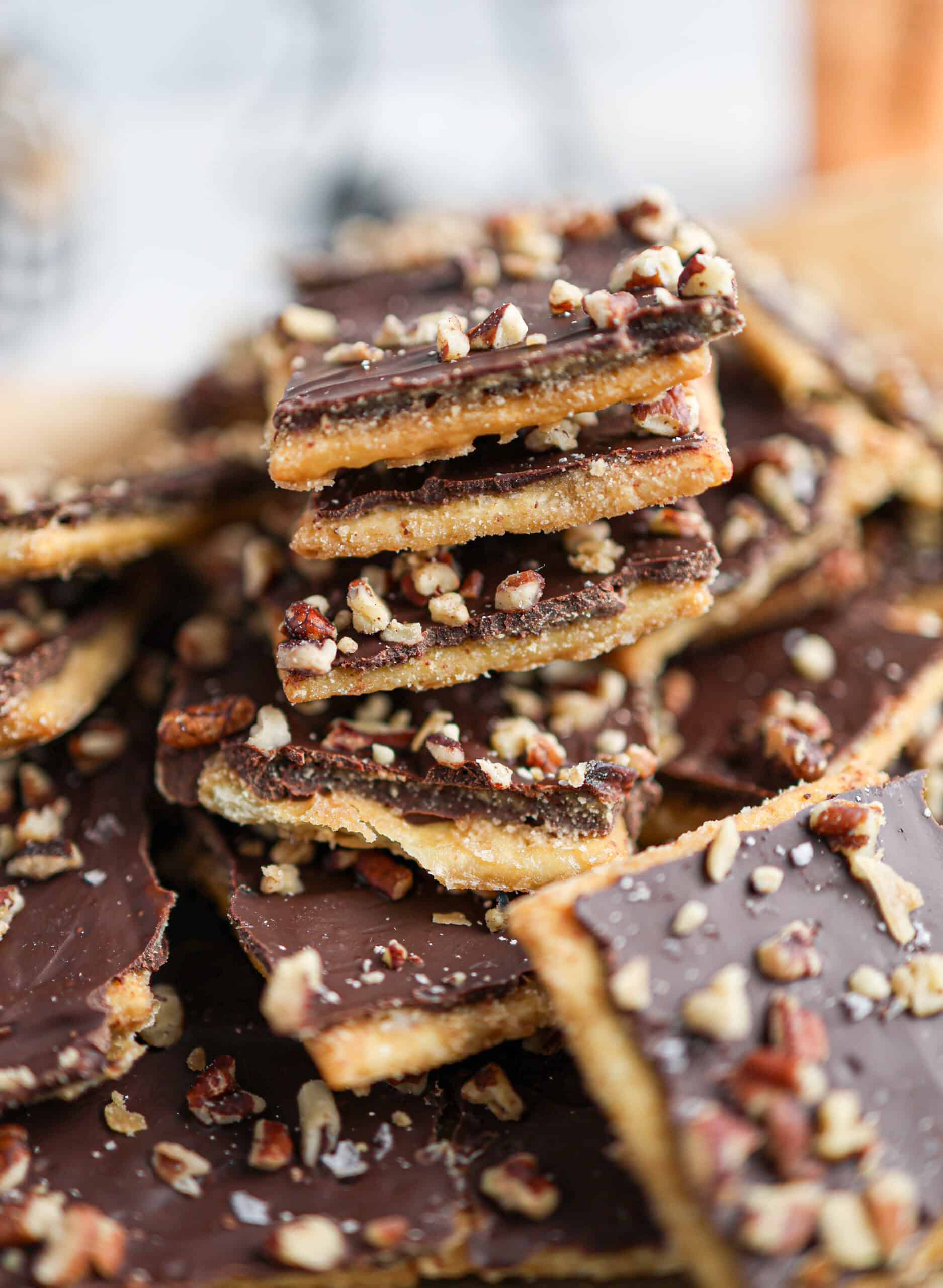 Close-up of stacked chocolate toffee bars, also known as christmas crack, topped with chopped nuts.